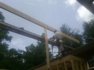 Carpenter setting a ridge beam over a new addition frame — Ice Dam Removal by Roofing Brothers in Ida
