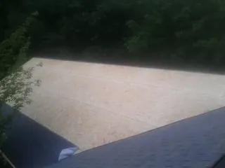 New OSB roof sheathing installed beside an existing shingle roof in Ida