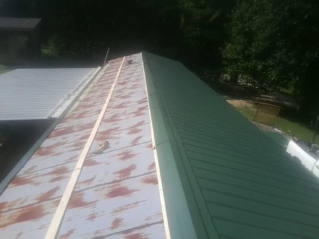 Old rusted panels beside newly installed green metal roofing — Wind Damage Roof Repair by Roofing Brothers in Ida