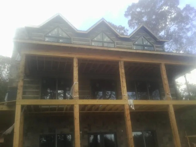 Dormers and porch framing on a large log home under construction — Roof Coating work by our crew in Ida