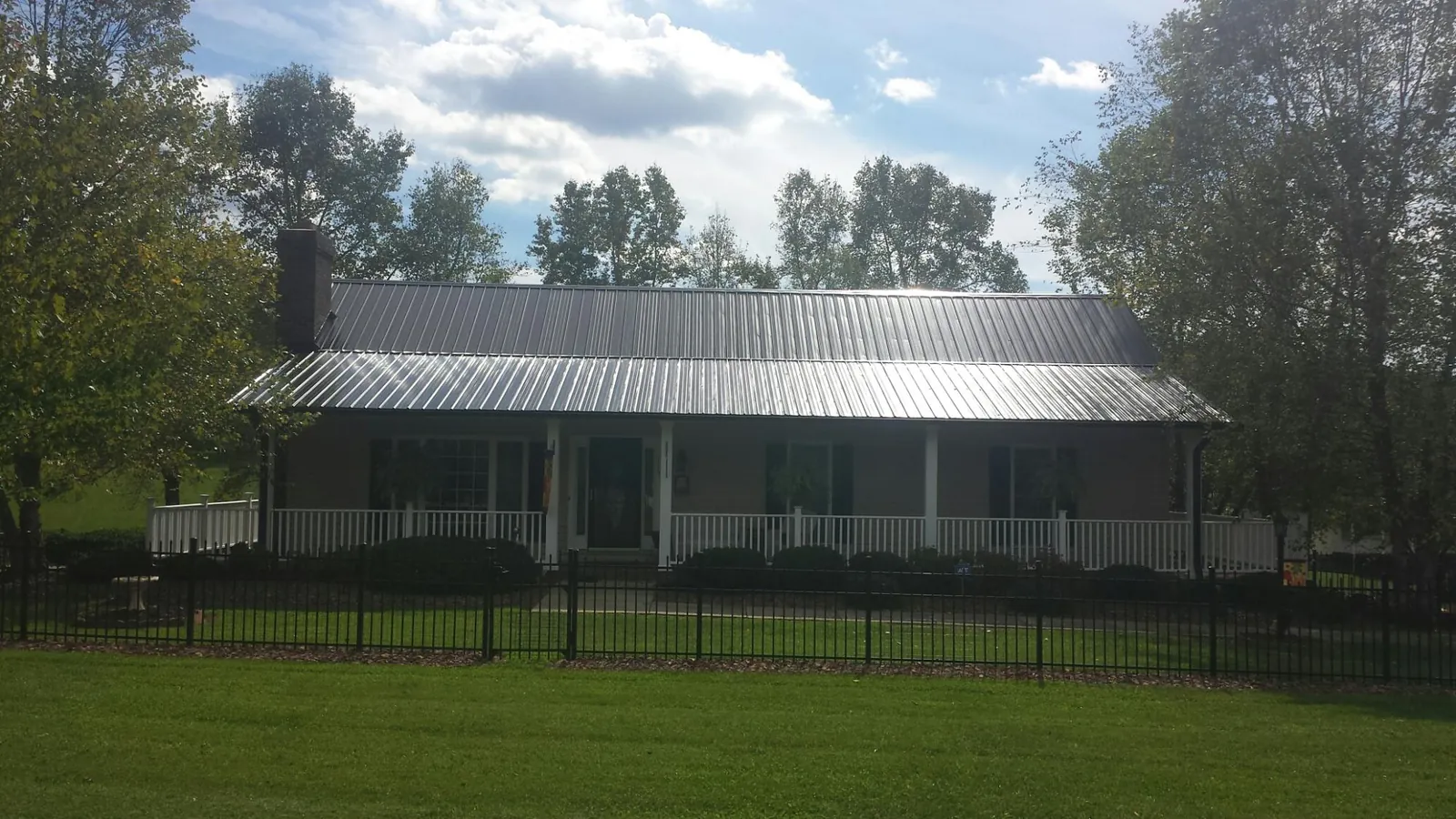 Gray metal roof on a brick ranch with a full width front porch — Gutter Guard Installation work by our crew in Ida