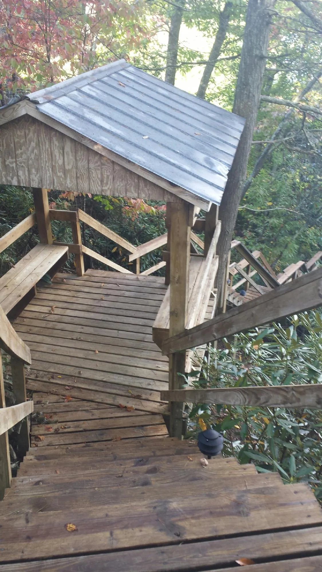 Metal roofed shelter over wooden steps on a wooded walkway — Skylight Repair & Installation work by our crew in Ida