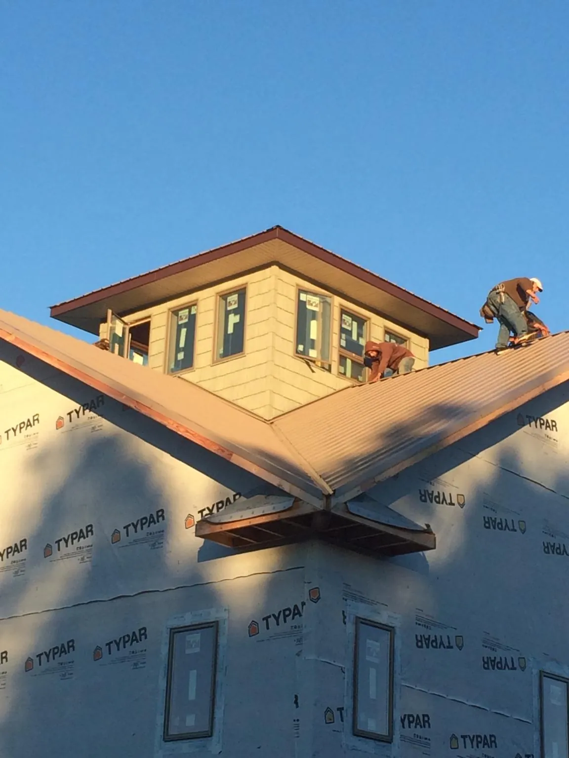 Roofers working around a rooftop cupola on a new metal roof at sunset — Roof Waterproofing in Ida by Roofing Brothers
